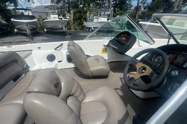 Slide: The Image of 2002 Triton 190-FS boat interior with beige seating and steering wheel, parked among other boats. - 15