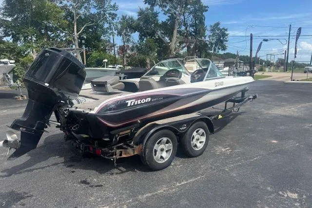 Slide: The Image of 2002 Triton 190-FS boat on trailer, parked outdoors, with visible outboard motor. - 2