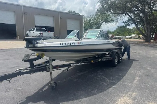 Slide: The Image of 2002 Triton 190-FS boat on trailer, parked outside a garage with a person inspecting. - 3