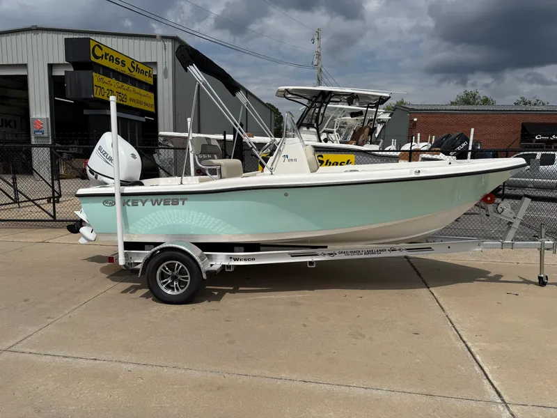 The Image of 2025 Key West 179 FS boat on trailer, parked outside dealership under cloudy sky. - 0