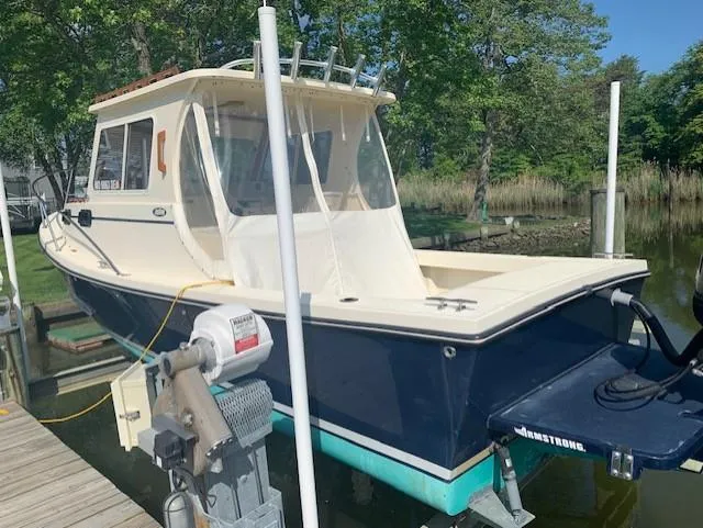 Slide: The Image of 2011 Eastern 24 Explorer boat docked, featuring a cabin and outboard motor, surrounded by greenery. - 3