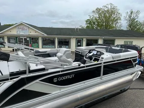 Slide: The Image of 2025 Sweetwater 2286SFL pontoon boat with sleek design, docked near a building. - 11