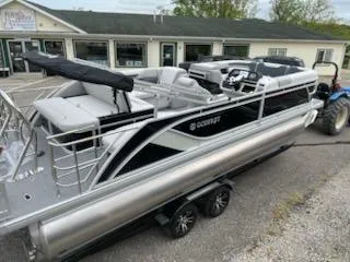 Slide: The Image of 2025 Sweetwater 2286SFL pontoon boat on trailer, parked outside a building. - 12
