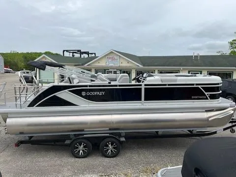 Slide: The Image of 2025 Sweetwater 2286SFL pontoon boat on trailer, parked outside a building. - 13