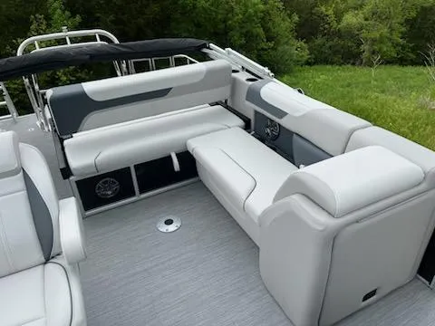 Slide: The Image of 2025 Sweetwater 2286SFL pontoon boat interior with gray seating and lush green background. - 18