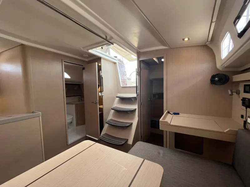 Slide: The Image of 2023 Beneteau Oceanis 40.1 interior with modern design, featuring stairs, table, and seating area. - 16