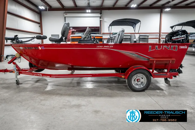 Slide: The Image of 2021 Lund 1650 ANG SS red fishing boat on trailer in indoor showroom. - 9