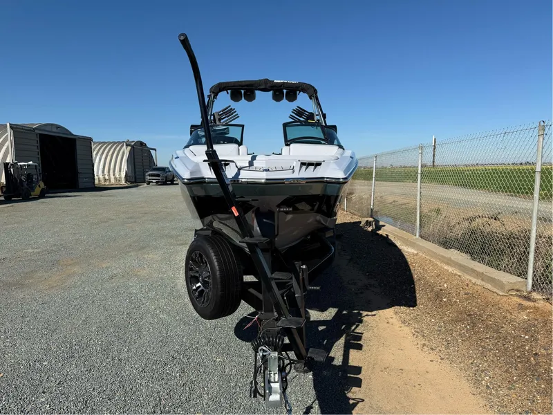 Slide: The Image of 2024 MasterCraft XStar S boat on trailer, parked outdoors under clear blue sky. - 2