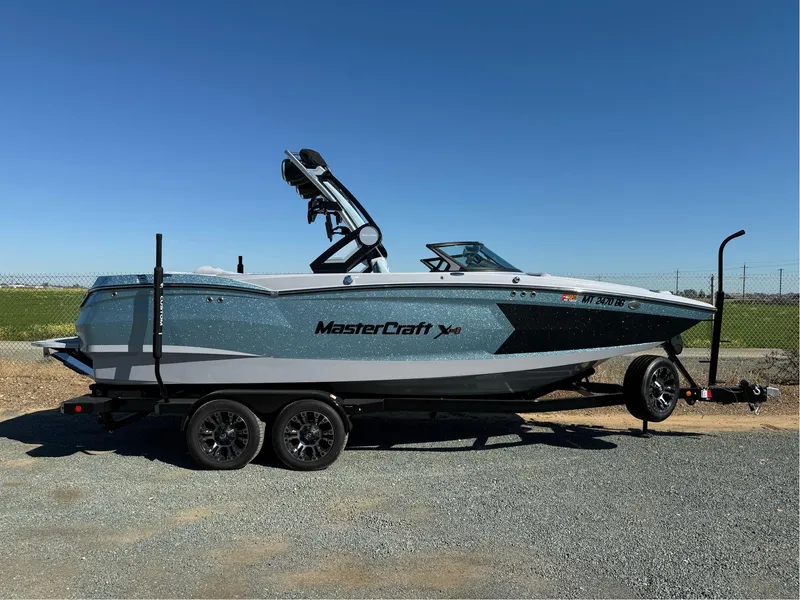 Slide: The Image of 2024 MasterCraft XStar S boat on trailer, side view, under clear blue sky. - 7