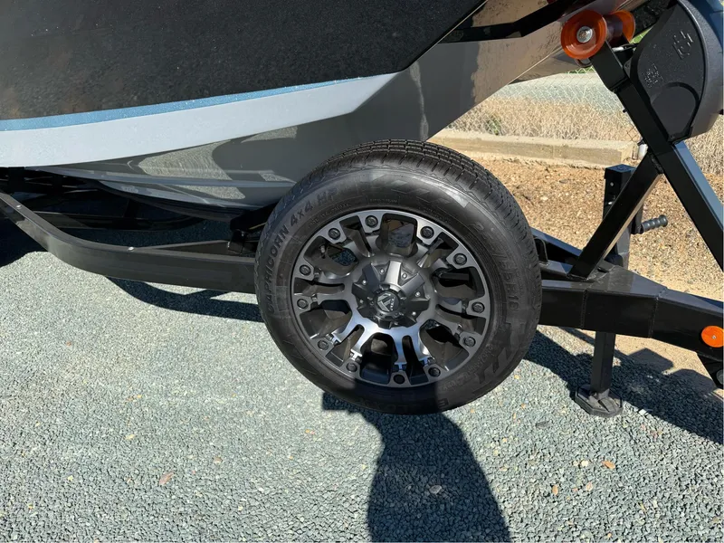 Slide: The Image of 2024 MasterCraft XStar S trailer wheel on gravel surface. - 9
