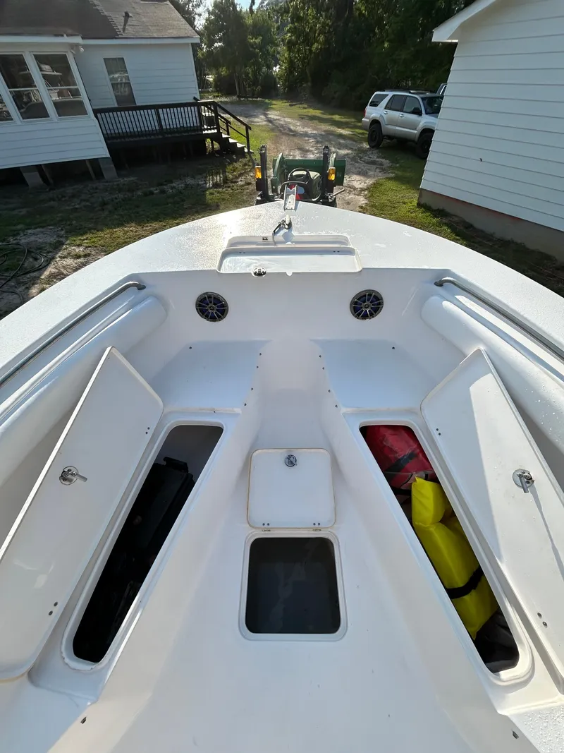 Slide: The Image of 2015 Tidewater 250 CC Adventure boat with open storage compartments, parked near houses. - 11
