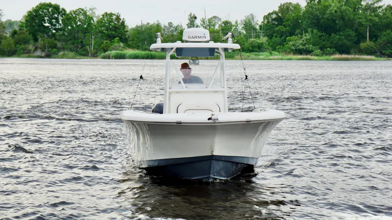 Slide: The Image of 2015 Tidewater 250 CC Adventure boat cruising on a river with lush green trees. - 2