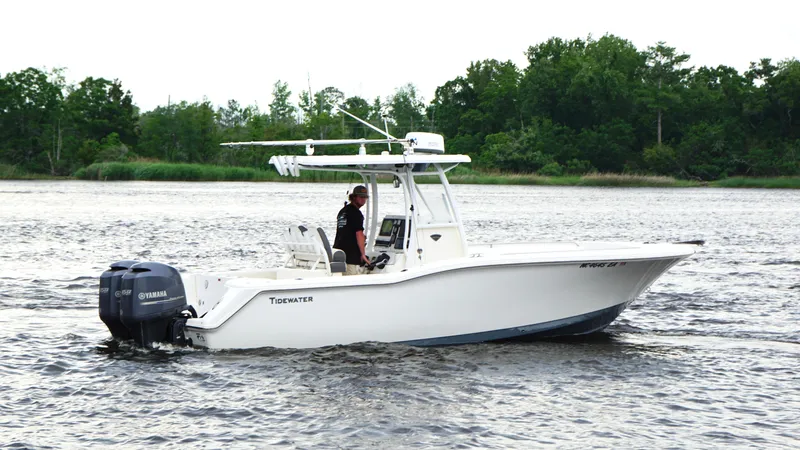 Slide: The Image of 2015 Tidewater 250 CC Adventure boat cruising on a river with lush green trees. - 3