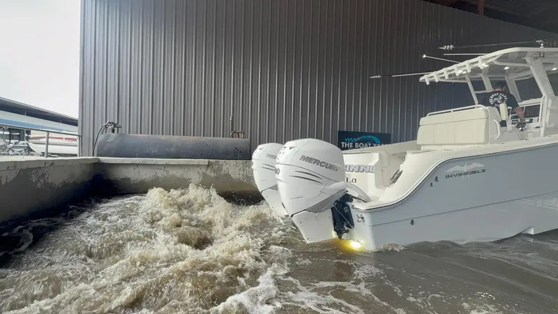 Slide: The Image of 2022 Invincible 33 Catamaran with dual Mercury engines in turbulent water near a dock. - 10