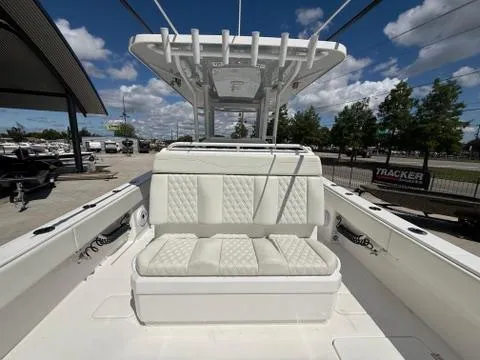 Slide: The Image of 2022 Invincible 33 Catamaran with cushioned seating and T-top under a clear sky. - 14