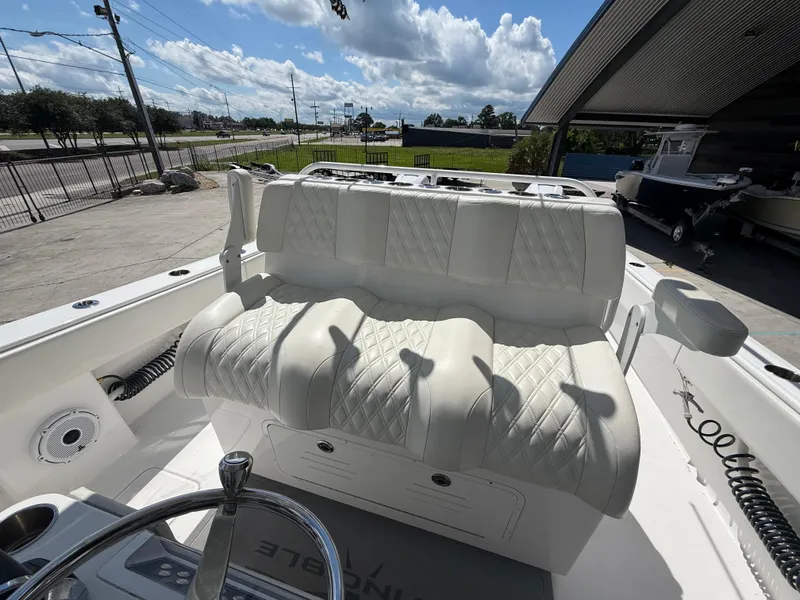 Slide: The Image of 2022 Invincible 33 Catamaran with white leather seating, parked outdoors under a clear sky. - 16