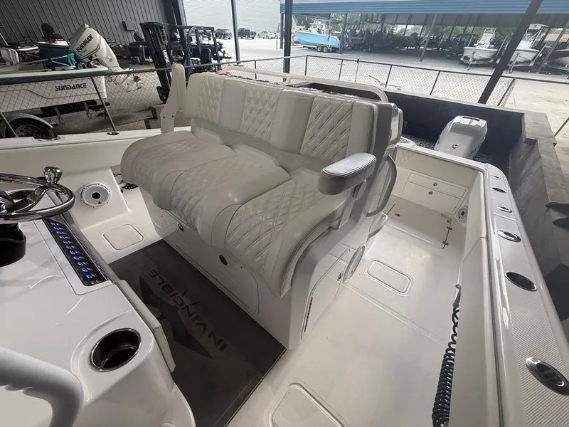 Slide: The Image of 2022 Invincible 33 Catamaran interior with white seating and steering wheel in a showroom. - 26