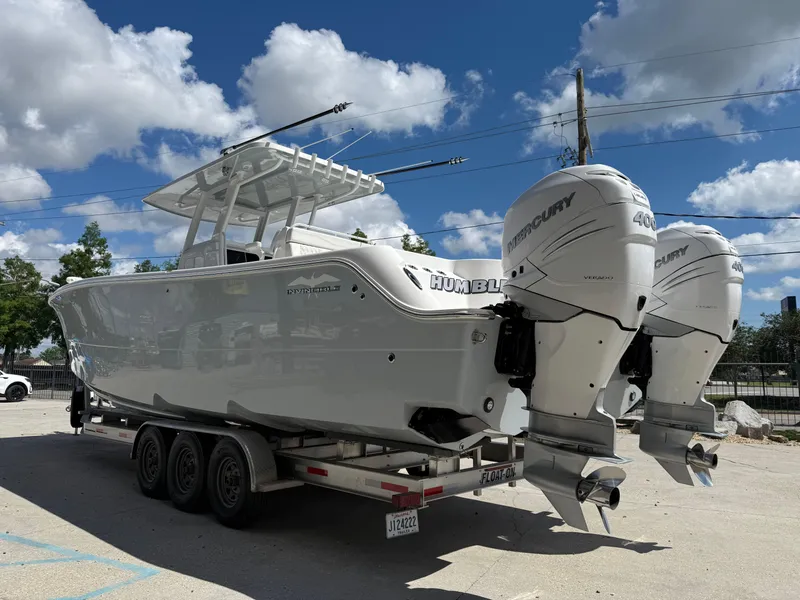 Slide: The Image of 2022 Invincible 33 Catamaran on trailer with twin Mercury outboard engines under a blue sky. - 5