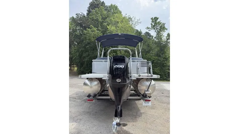 Slide: The Image of 2025 Tahoe LTZ Quad Lounger 23 pontoon boat with 200 HP engine, parked outdoors. - 1