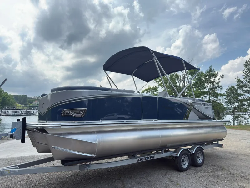 Slide: The Image of 2025 Tahoe LTZ Quad Lounger 23 pontoon boat on trailer, under cloudy sky. - 3