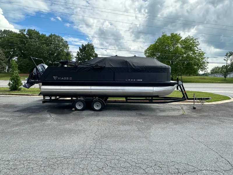 Slide: The Image of 2025 Viaggio Lago X-S pontoon boat on trailer, covered, parked outdoors. - 4