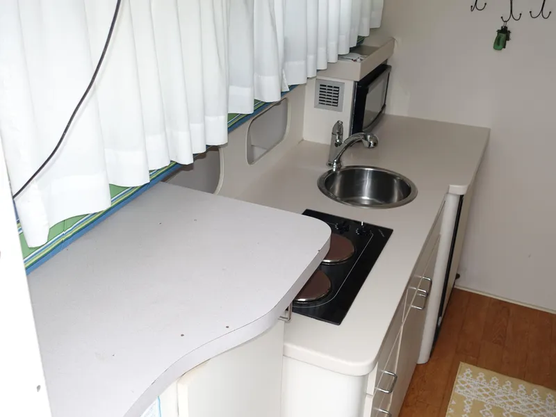 Slide: The Image of Compact kitchen area in a 1998 Mainship 31 Sedan Bridge boat, featuring sink and stove. - 10