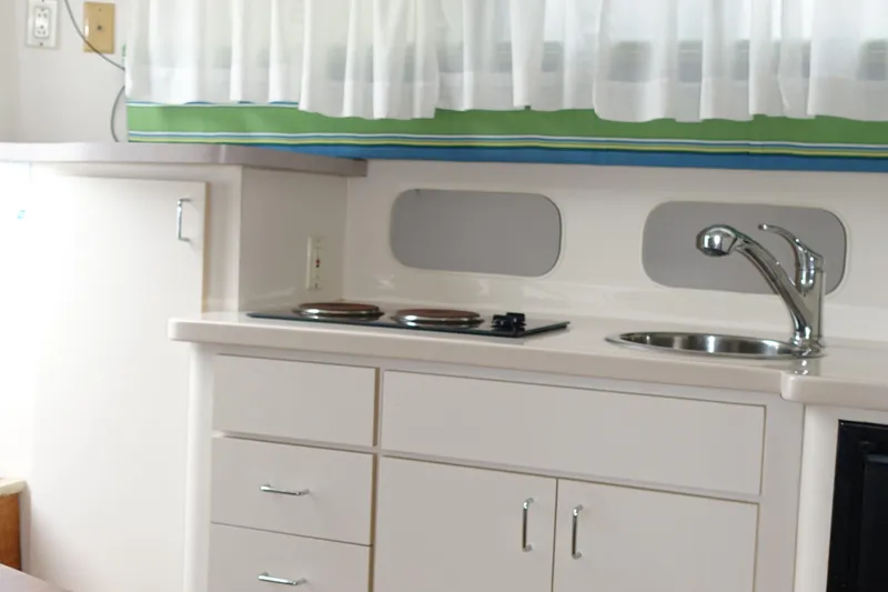 Slide: The Image of Compact kitchen area in a 1998 Mainship 31 Sedan Bridge boat, featuring stove and sink. - 12
