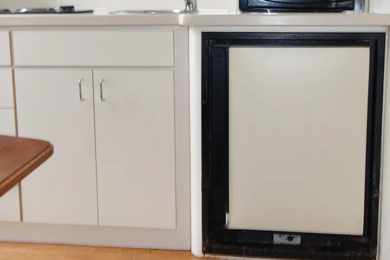 Slide: The Image of Interior view of 1998 Mainship 31 Sedan Bridge kitchen area with cabinets and fridge. - 13