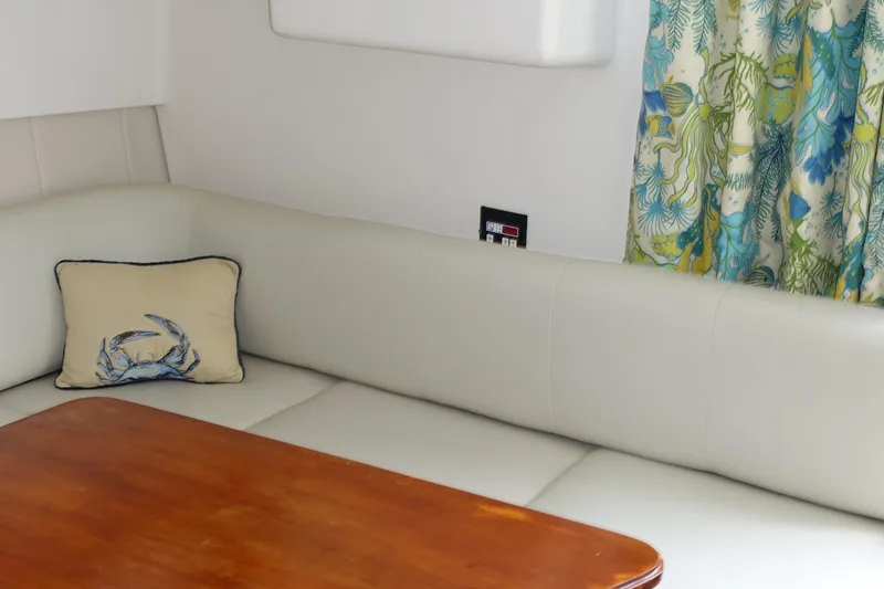 Slide: The Image of Interior of 1998 Mainship 31 Sedan Bridge with cushioned seating and wooden table. - 17