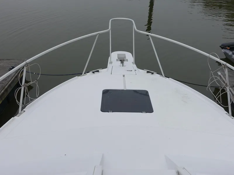Slide: The Image of 1998 Mainship 31 Sedan Bridge boat deck with railing, docked on calm water. - 2