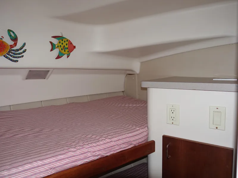 Slide: The Image of 1998 Mainship 31 Sedan Bridge cabin interior with bed, colorful wall decor, and wooden cabinetry. - 24