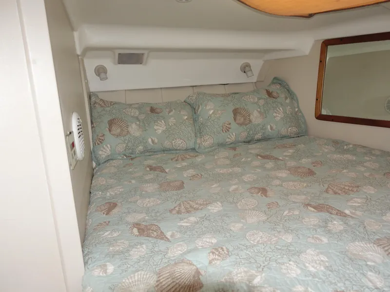 Slide: The Image of 1998 Mainship 31 Sedan Bridge cabin with seashell-patterned bedding. - 26