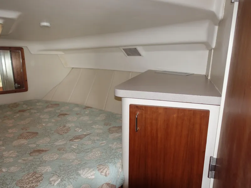 Slide: The Image of 1998 Mainship 31 Sedan Bridge cabin interior with bed and wooden cabinet. - 28