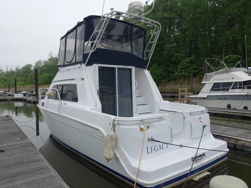 Slide: The Image of 1998 Mainship 31 Sedan Bridge docked at marina, featuring upper deck and cabin. - 32