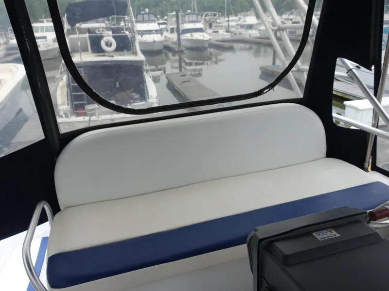 Slide: The Image of 1998 Mainship 31 Sedan Bridge interior with marina view, featuring a cushioned seating area. - 7