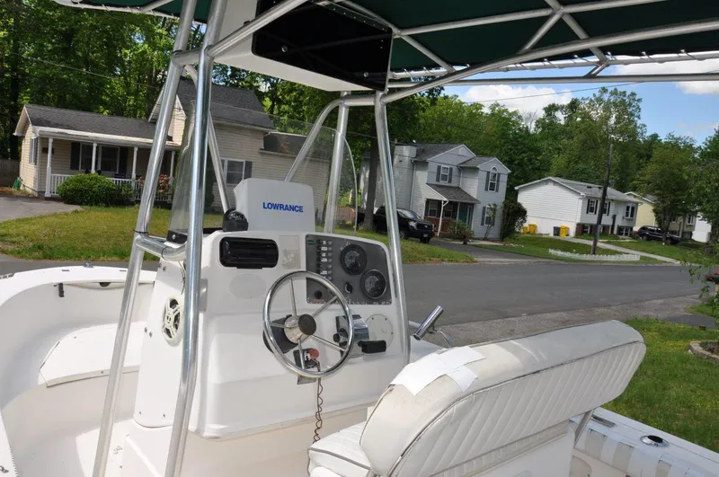 Slide: The Image of 2003 Trophy 1903 Center Console boat with steering wheel and navigation equipment, parked in a residential area. - 10