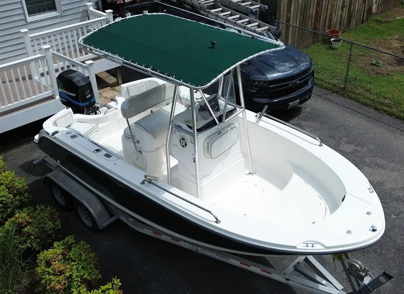 Slide: The Image of 2003 Trophy 1903 Center Console boat with green canopy on trailer, parked in driveway. - 7