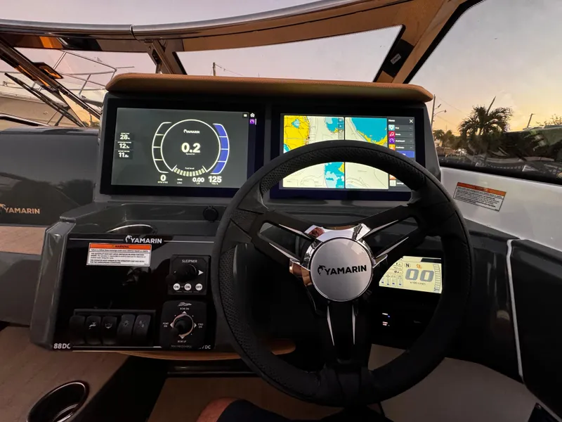 Slide: The Image of Yamarin 88 DC 2023 dashboard with digital displays and steering wheel at sunset. - 13