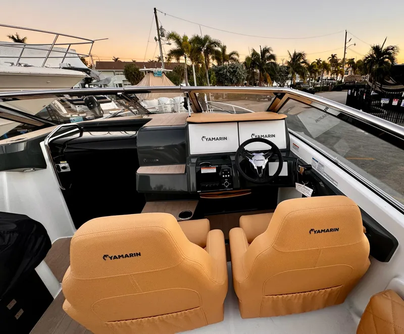Slide: The Image of 2023 Yamarin 88 DC boat interior with tan seats and modern dashboard at sunset. - 21