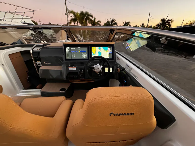 Slide: The Image of 2023 Yamarin 88 DC boat cockpit with advanced navigation system and tan seats at sunset. - 4