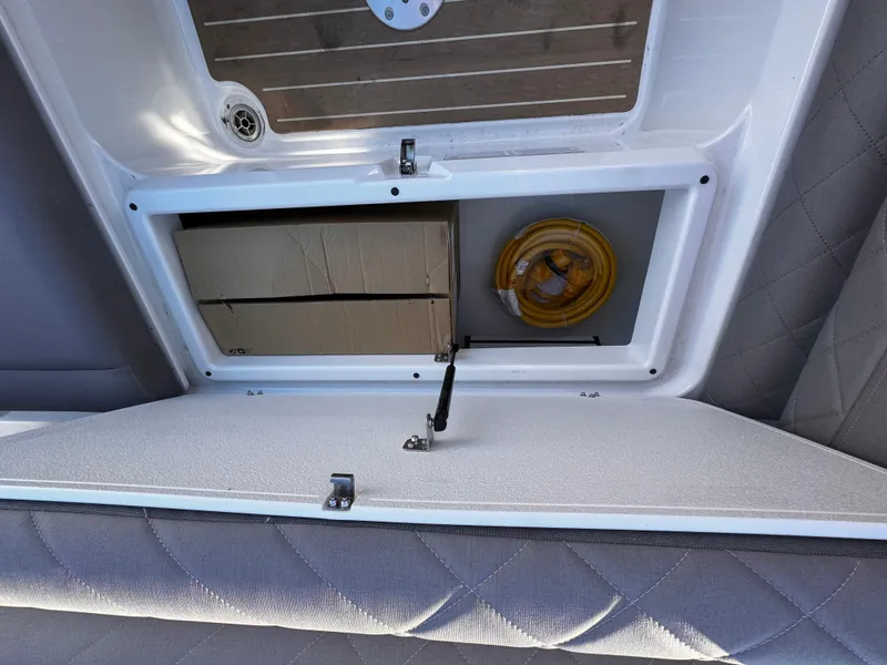 Slide: The Image of Open storage compartment in 2025 Yamarin 80DC boat, containing a box and coiled rope. - 12