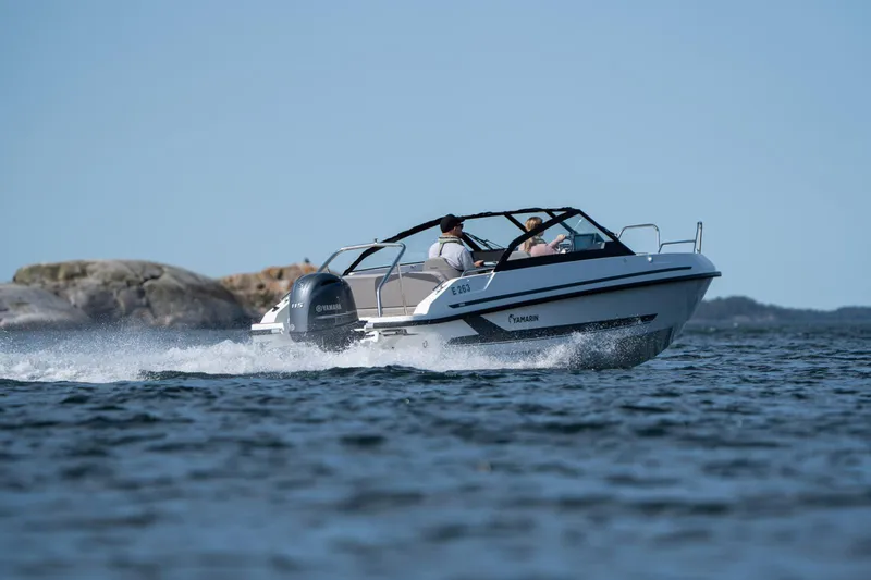 Slide: The Image of 2026 Yamarin 59 boat cruising on open water with rocky shoreline in background. - 6