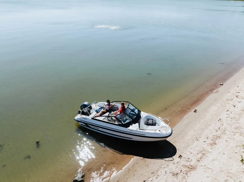 Slide: The Image of 2026 Yamarin 59 boat docked on a sandy beach with two people relaxing onboard. - 8