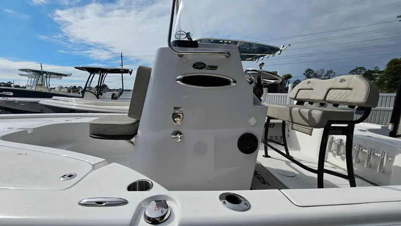 Slide: The Image of 2024 Sea Pro 210 Bay boat interior with seating and console, under a partly cloudy sky. - 17