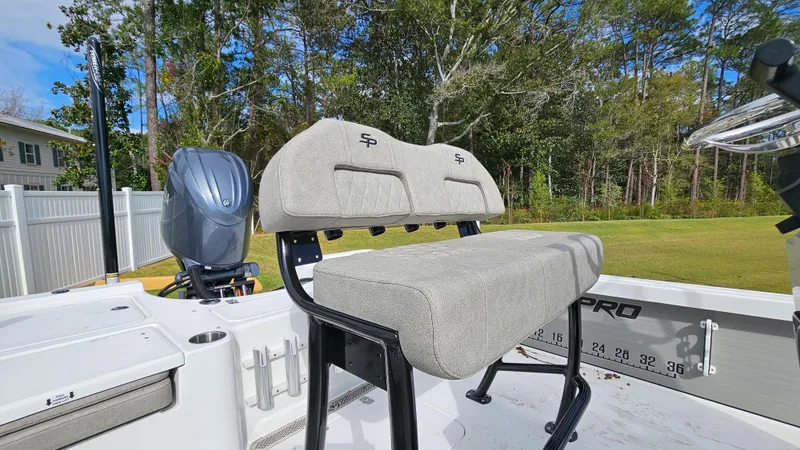 Slide: The Image of 2024 Sea Pro 210 Bay boat with cushioned seating and outboard motor, set in a grassy area. - 6
