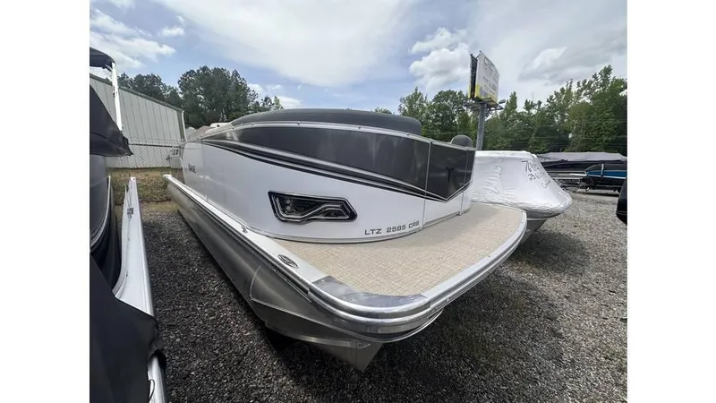 The Image of 2025 Tahoe Pontoon LTZ Cruise Rear Bench, sleek design, parked outdoors on gravel. - 0