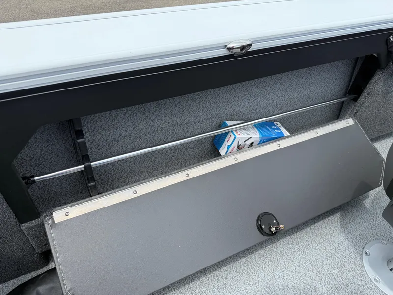 Slide: The Image of 2025 Lund Fisherman 2075 boat interior storage compartment with a box of marine supplies. - 14