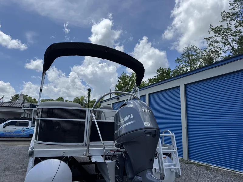 Slide: The Image of 2022 Bennington 22 SSR pontoon boat with Yamaha motor, parked near blue storage units. - 2