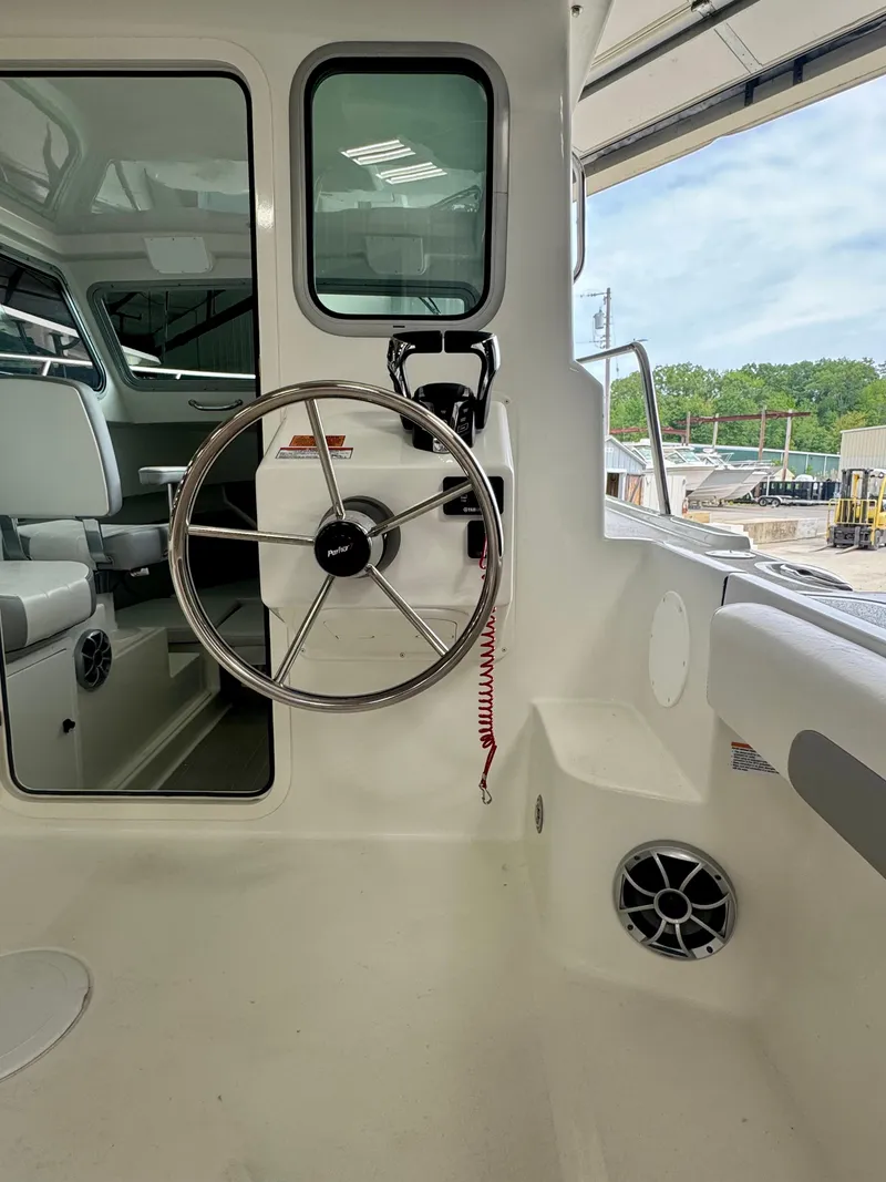 Slide: The Image of 2025 Parker 2420 Sport Cabin boat interior with steering wheel and seating. - 11