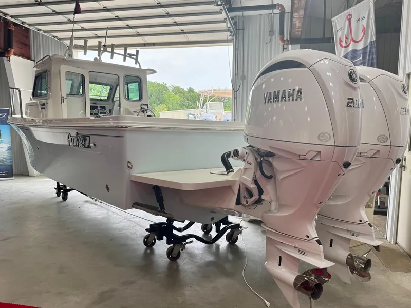Slide: The Image of 2025 Parker 2420 Sport Cabin boat with twin Yamaha engines in a garage. - 2
